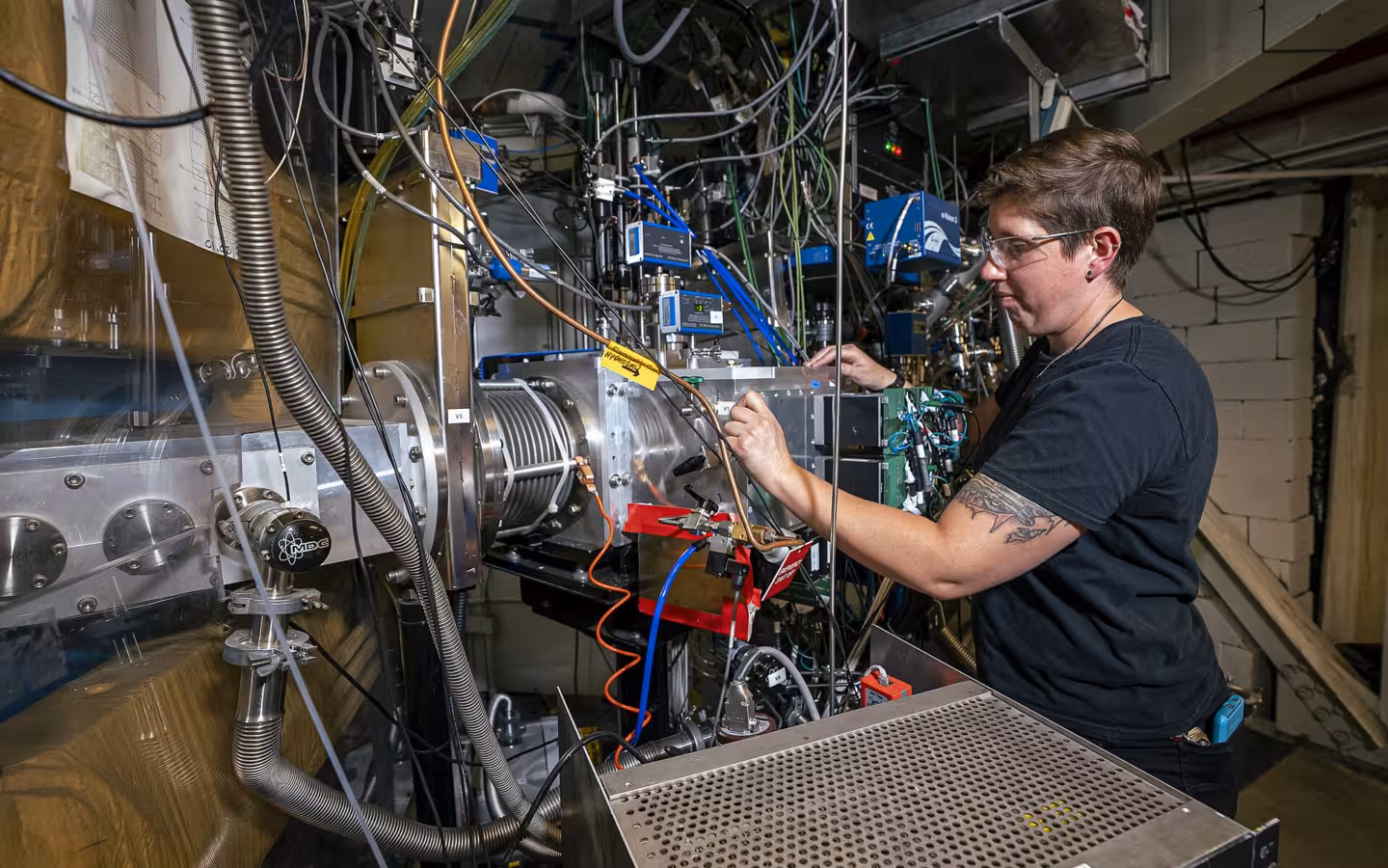 Jacklyn Gates works on the Berkeley Gas-filled Separator amid crowded laboratory equipment.