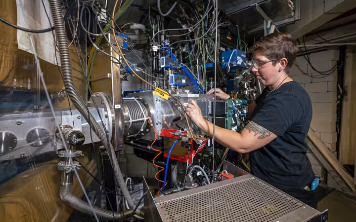 Jacklyn Gates works on the Berkeley Gas-filled Separator amid crowded laboratory equipment.