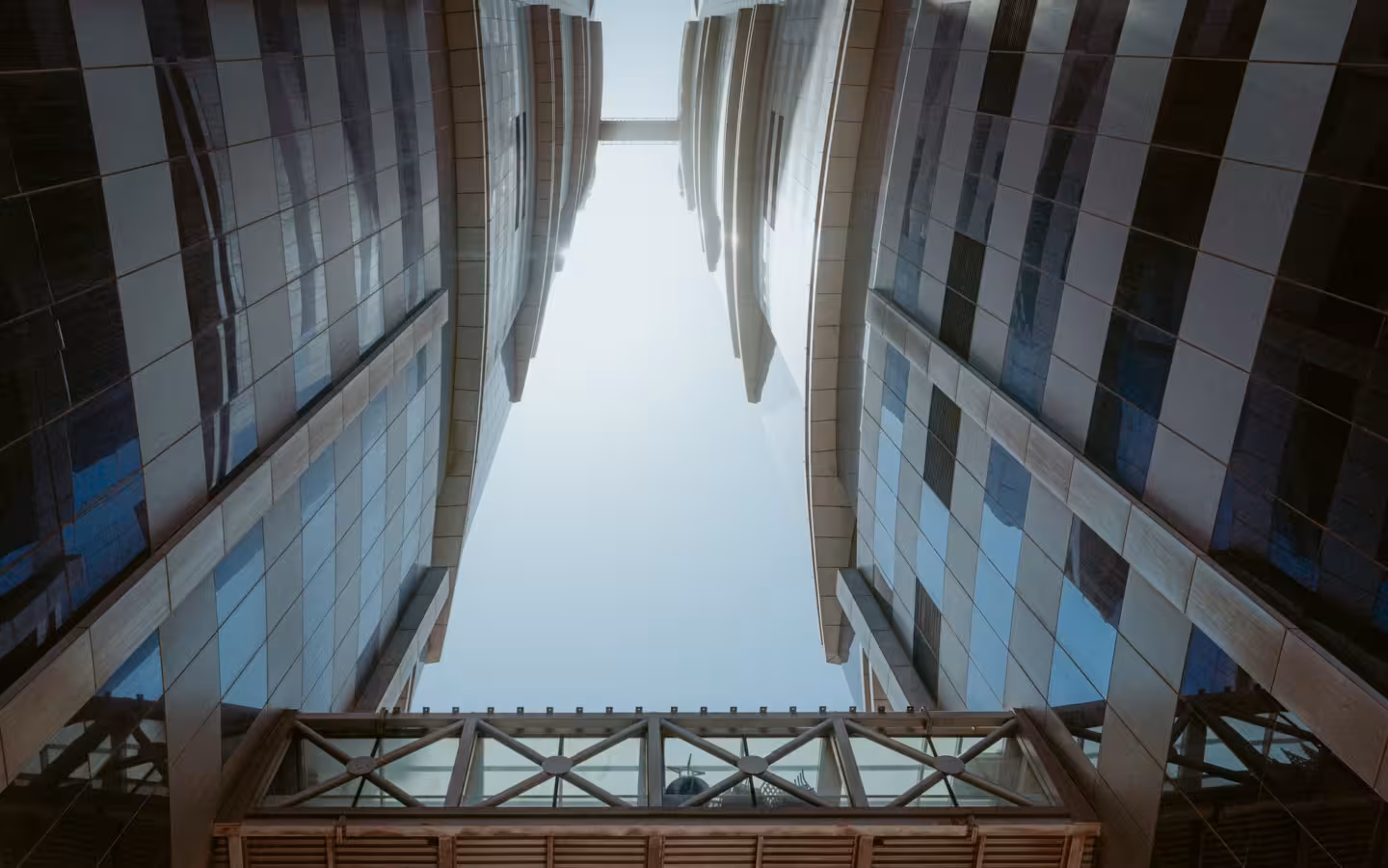 Modern Dubai skyscrapers rise around a sky bridge against a bright sky
