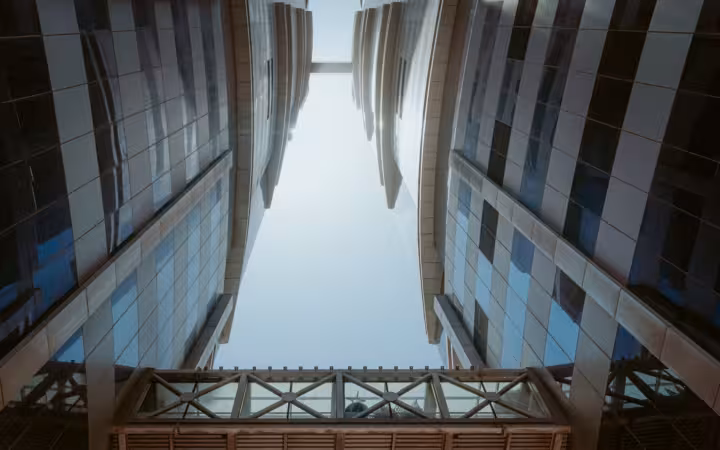 Modern Dubai skyscrapers rise around a sky bridge against a bright sky
