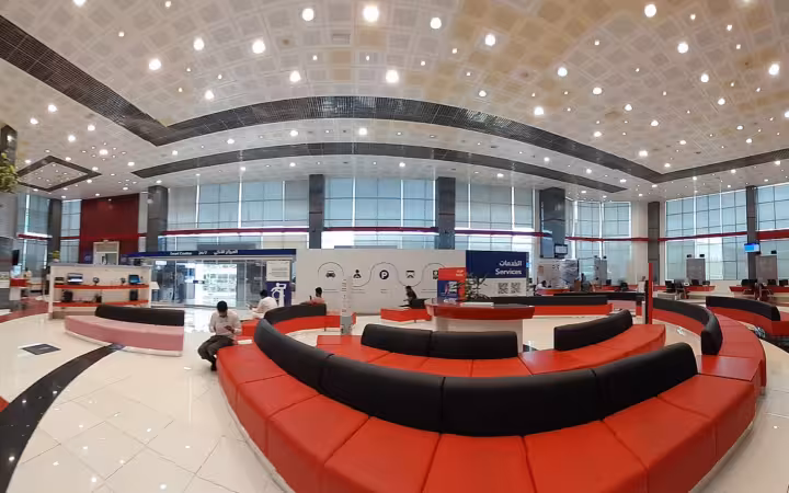 Wide-angle interior view of a modern customer service waiting room with red seating.