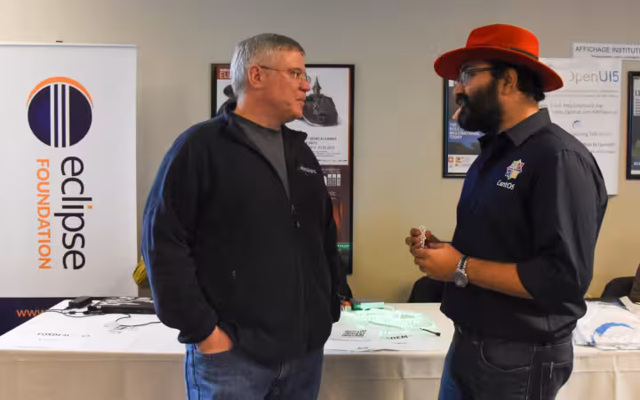 Mike Milinkovich and KB Singh talking beside an Eclipse Foundation banner.
