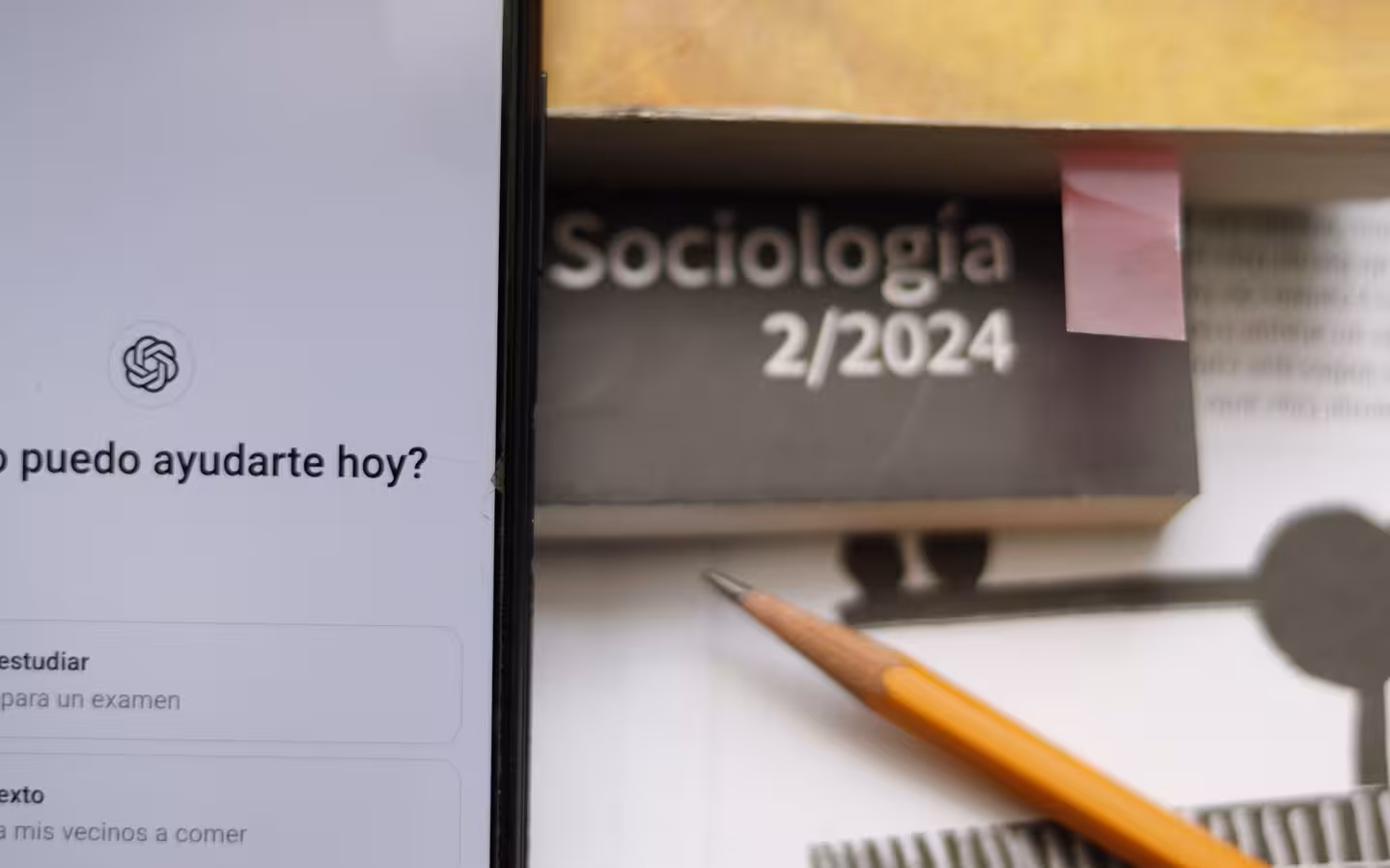 A phone displaying ChatGPT beside a sociology book and pencil