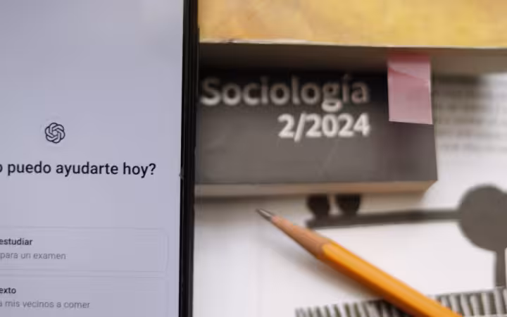 A phone displaying ChatGPT beside a sociology book and pencil