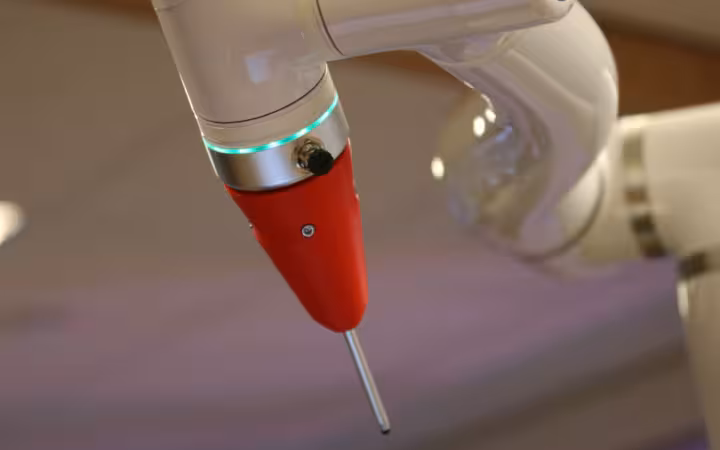 Close-up of a white robotic arm with a red tool attachment