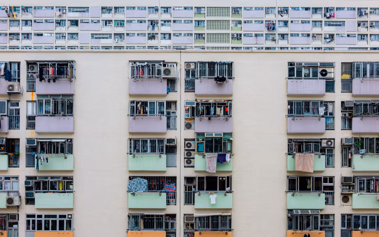 A colorful urban apartment building facade featuring uniform balconies and windows.