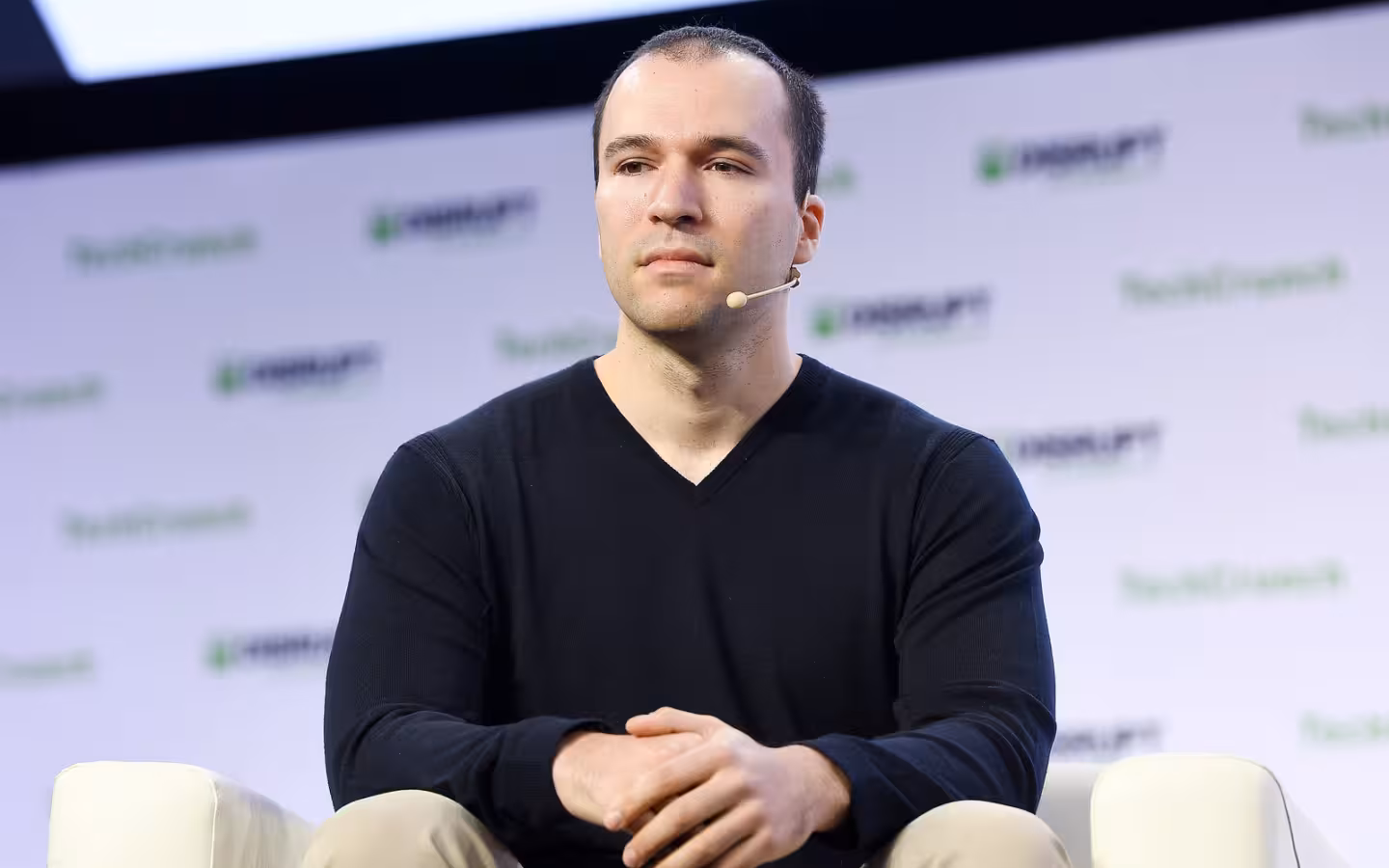 OpenAI co-founder Greg Brockman sits onstage wearing a headset microphone.