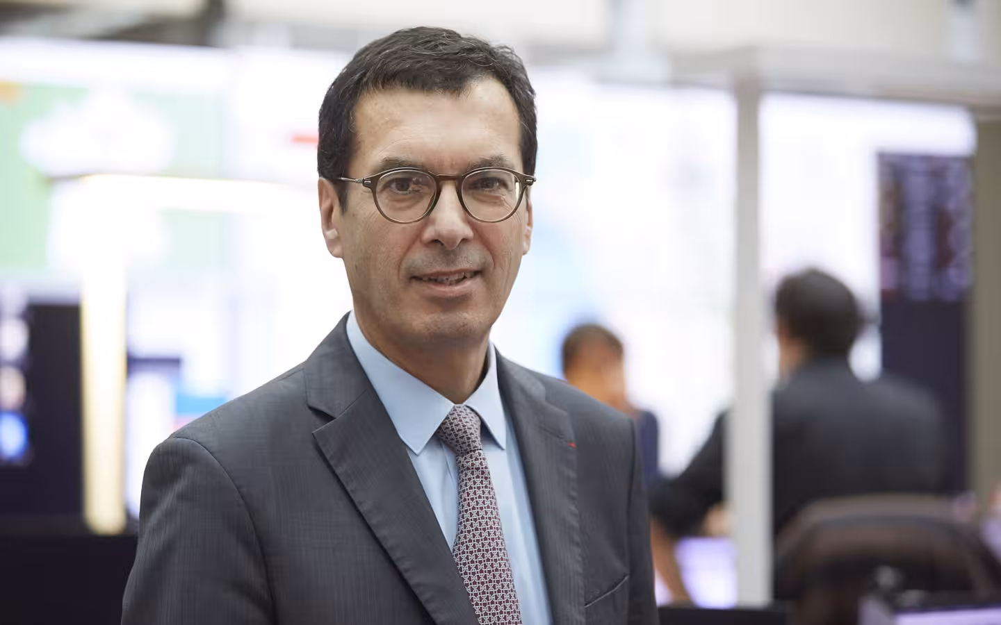 Man in suit and glasses looking at camera in office