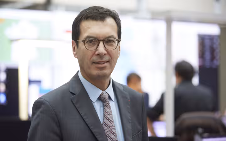 Man in suit and glasses looking at camera in office