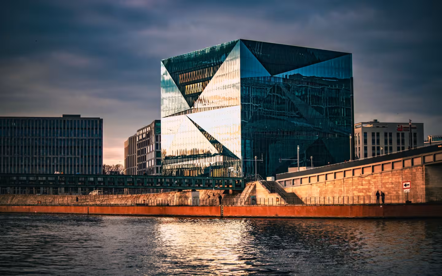 A glass-fronted modern building beside the Berliner waterfront at sunset