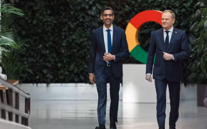 Sundar Pichai and Donald Tusk walk past a Google logo in Warsaw.