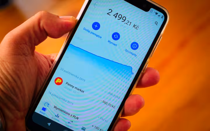 A hand holds a Motorola One smartphone displaying the Revolut app.