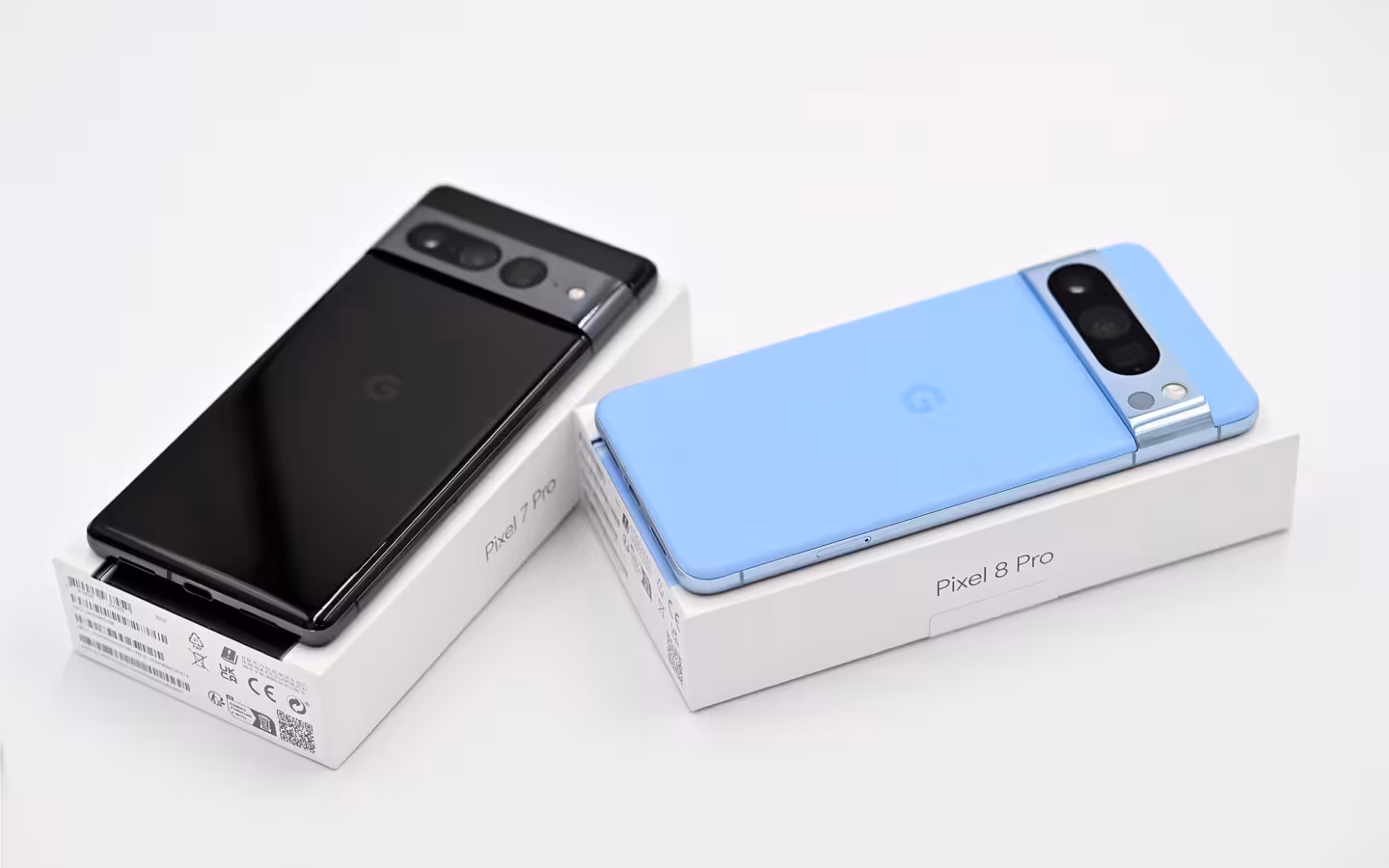 A black Google Pixel 7 Pro and blue Pixel 8 Pro rest on boxes.