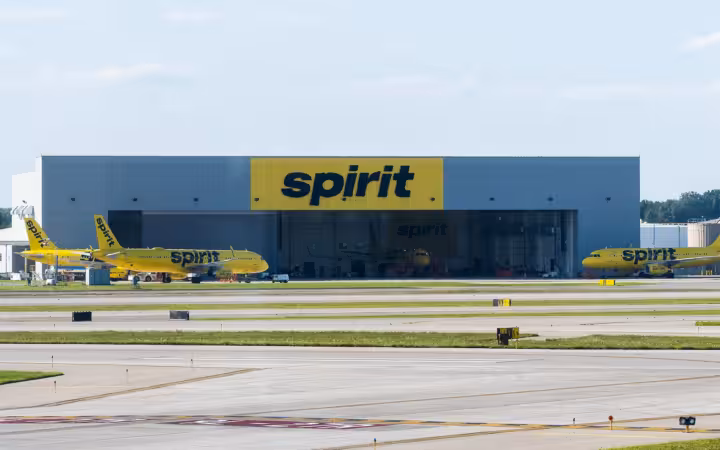Spirit Airlines jets parked outside a branded hangar across an airport runway