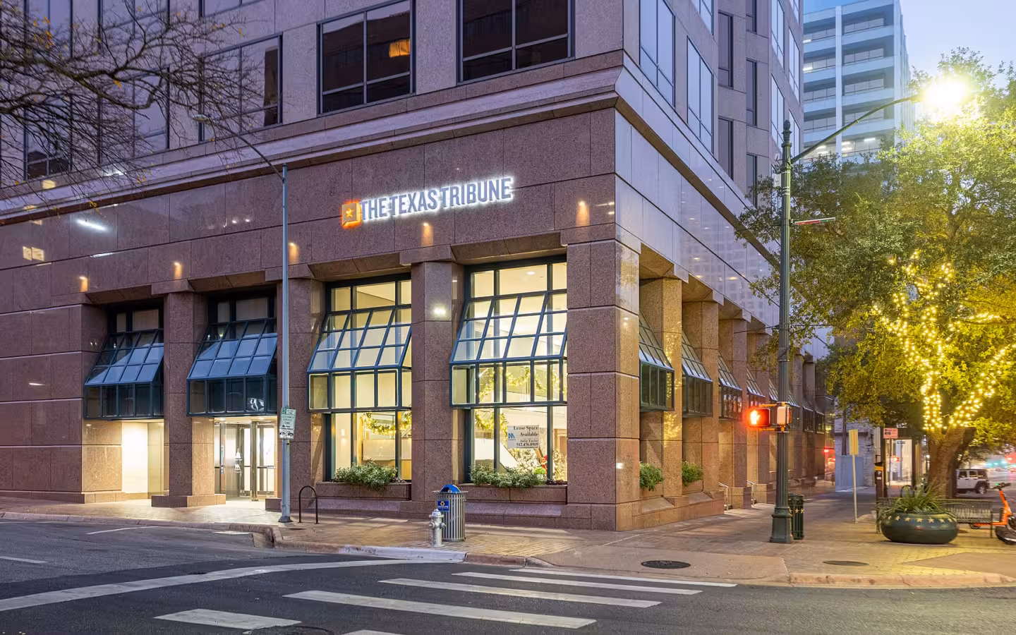 The Texas Tribune sign on an office building along an Austin street at dusk