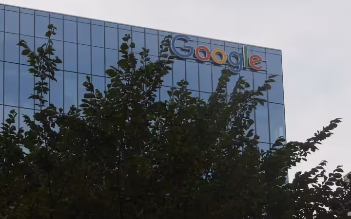 Google sign on a glass Toronto office building, partly obscured by tree branches