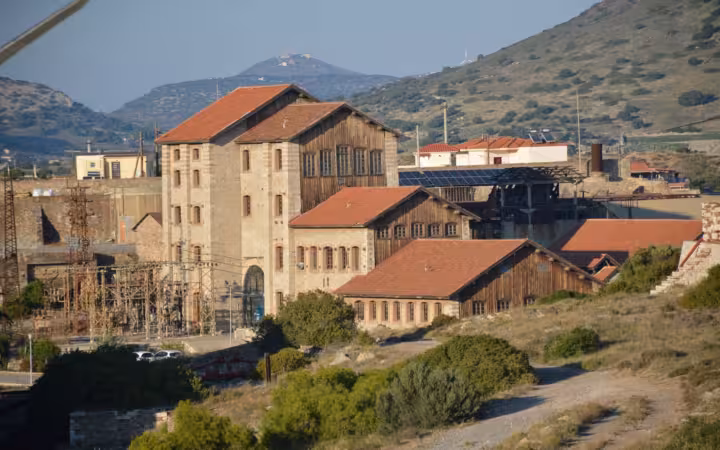Historic industrial buildings at Laurium technological park amid scrubby hills