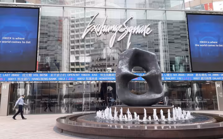 A sculpture and fountain stand outside Exchange Square beneath HKEX displays.