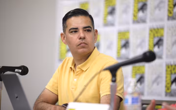 Robert Garcia sits at a San Diego Comic Con panel with microphones.