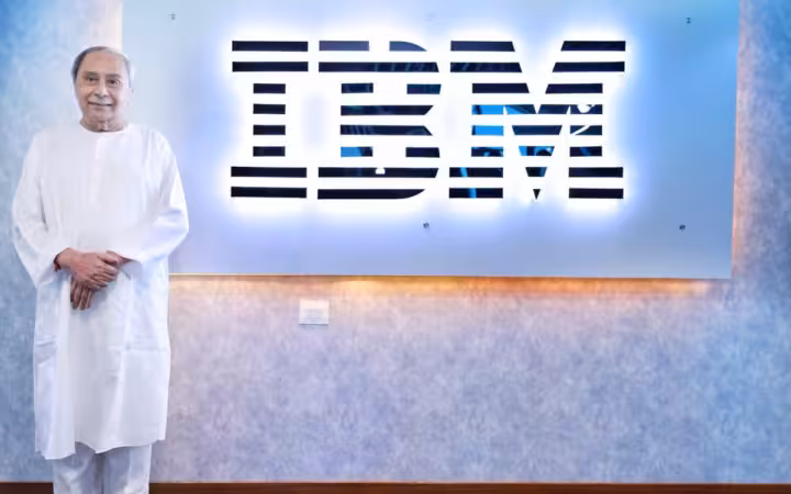 Odisha CM stands beside an illuminated IBM sign at its Bhubaneswar office.