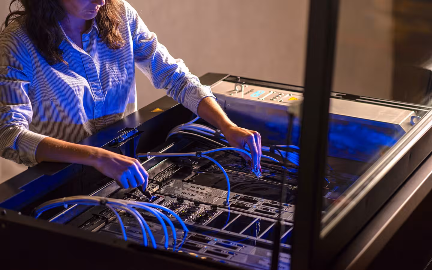 A technician works on Open Compute hardware in a Submer immersion cooling system.