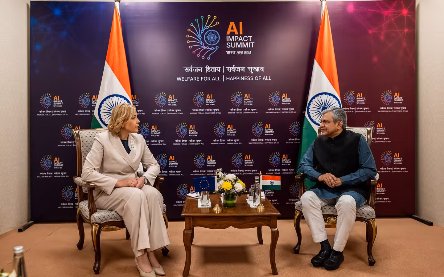 Ashwini Vaishnaw and Henna Virkkunen seated before AI Impact Summit signage and Indian flags
