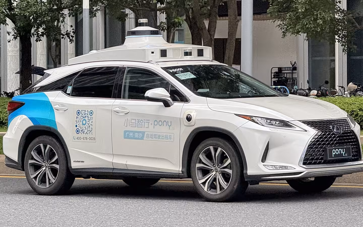 A white Pony.ai Lexus RX450h robotaxi on a tree-lined street.