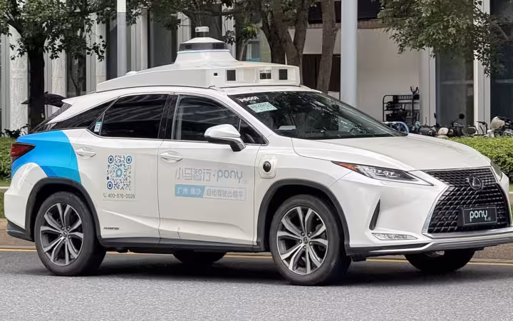 A white Pony.ai Lexus RX450h robotaxi on a tree-lined street.