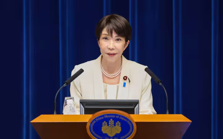 Sanae Takaichi speaks behind a lectern at a press conference.