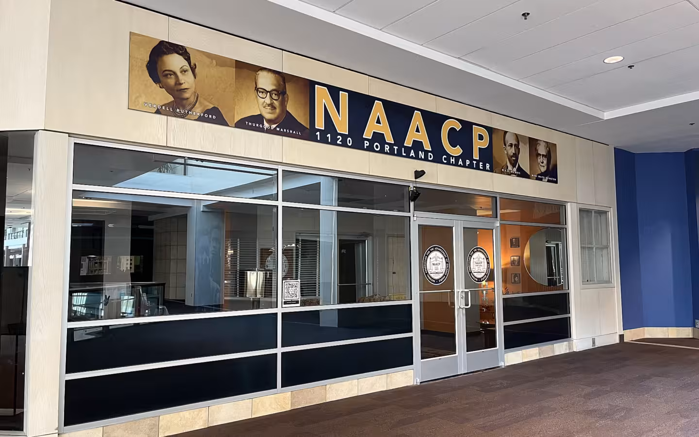 Glass-fronted Portland NAACP chapter office beneath a large blue sign