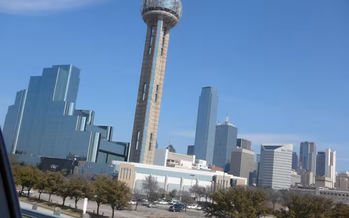 Dallas skyline with Reunion Tower above buildings and a parking lot