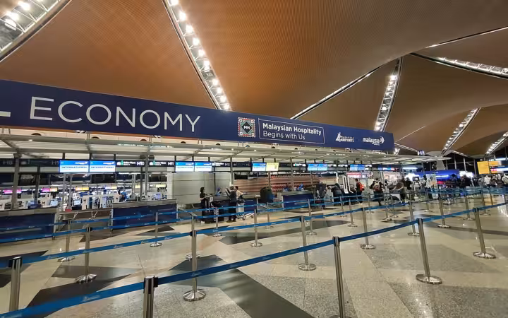 Kuala Lumpur International Airport check-in counters beneath a sweeping terminal ceiling