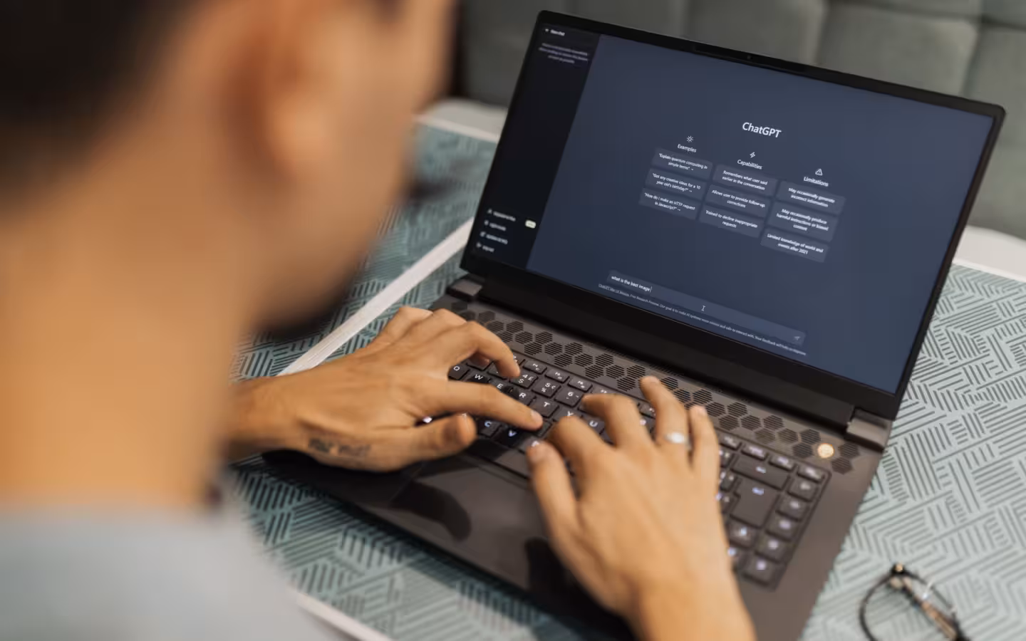 A focused individual typing on a laptop showing AI software interface