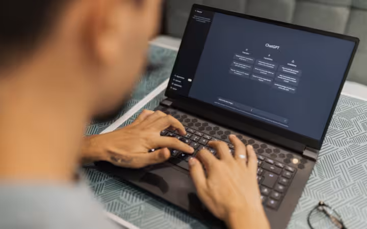 A focused individual typing on a laptop showing AI software interface