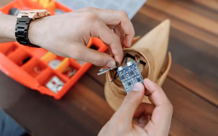 Hands adjust a microcontroller board inside a small DIY electronics project.