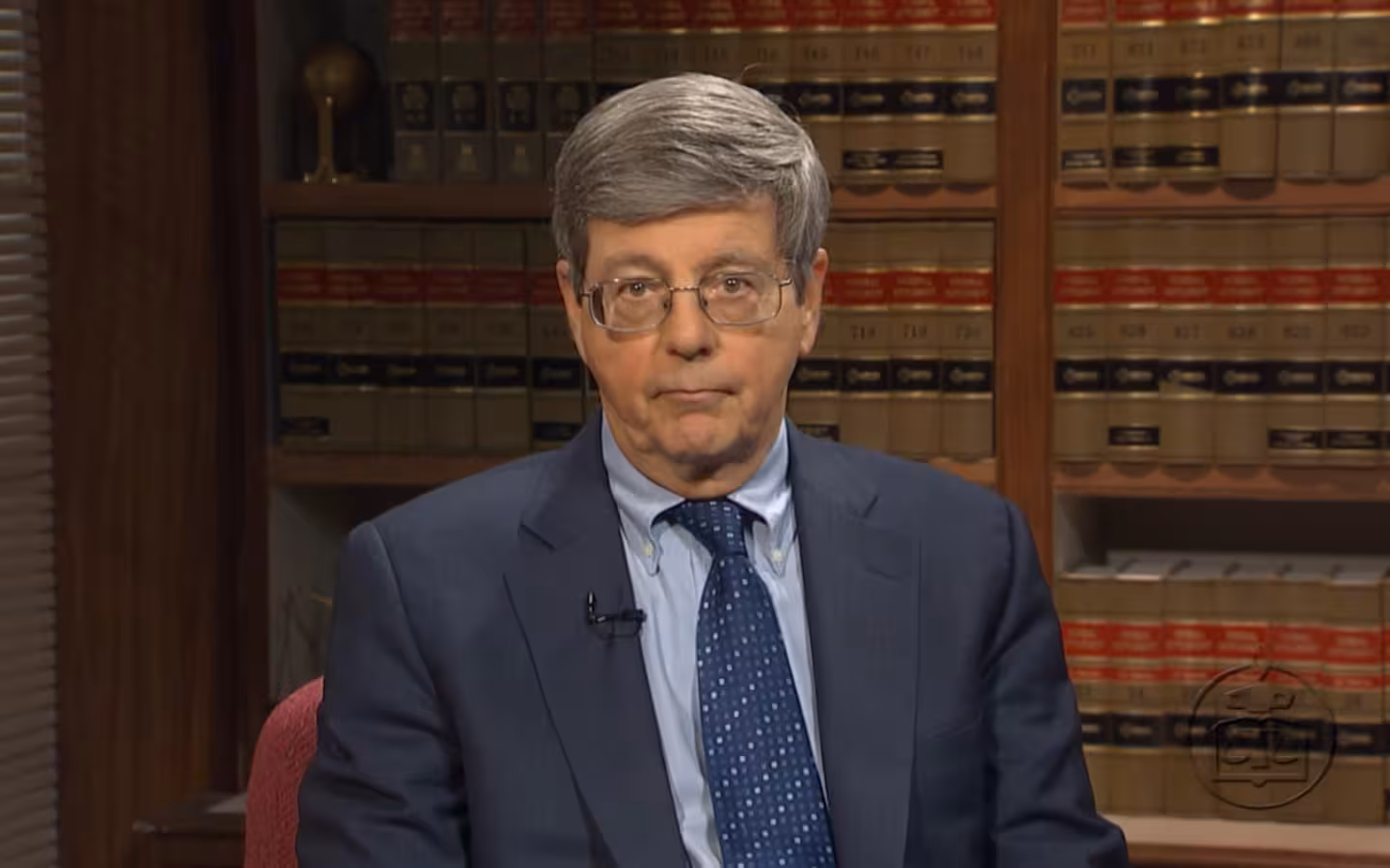 Judge John G. Koeltl seated before shelves of law books.