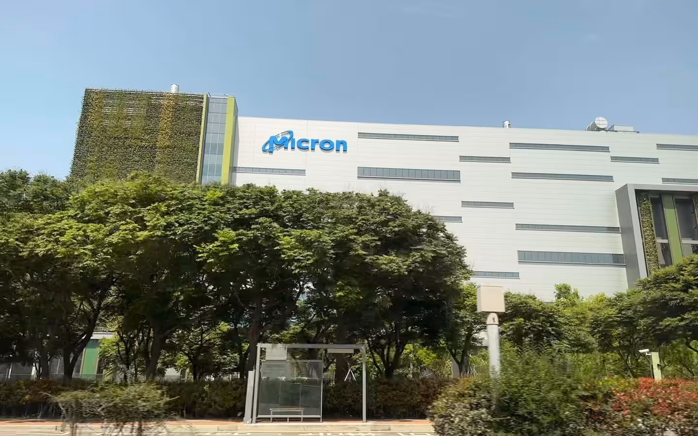 Micron fab in Taichung, Taiwan, behind roadside trees and a bus shelter