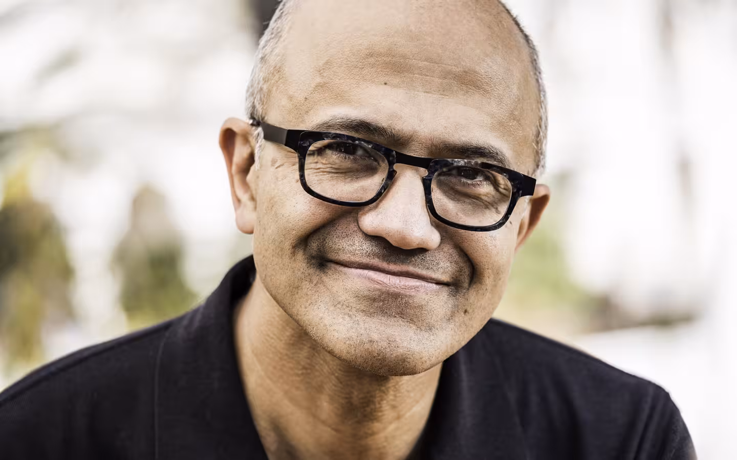Microsoft CEO Satya Nadella smiles in a close-up portrait.