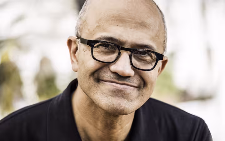 Microsoft CEO Satya Nadella smiles in a close-up portrait.