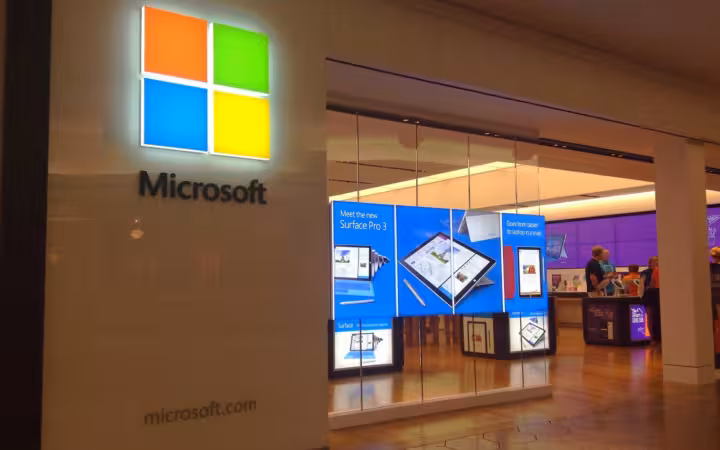 Microsoft Store entrance with an illuminated logo and Surface displays inside