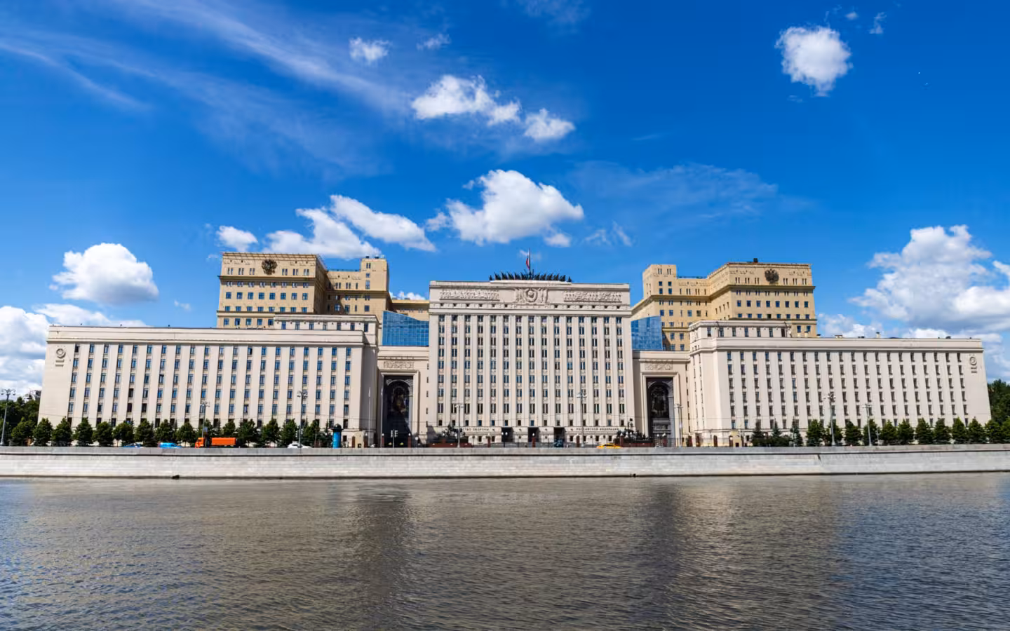 A large riverfront building beneath a blue sky with scattered clouds