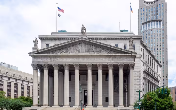 The New York County Courthouse’s columned facade rises above traffic on Foley Square.