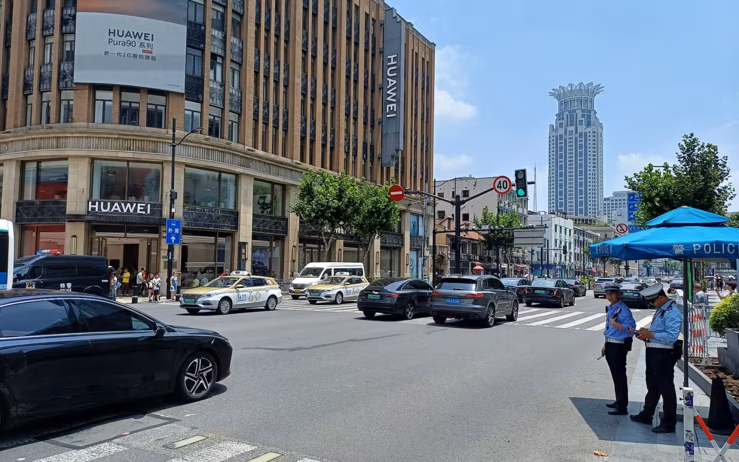 A Huawei-signed building beside a busy Shanghai street with cars and police officers