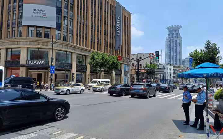 A Huawei-signed building beside a busy Shanghai street with cars and police officers
