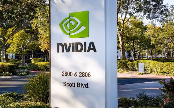 A large NVIDIA sign outside its Scott Boulevard headquarters campus, surrounded by trees.