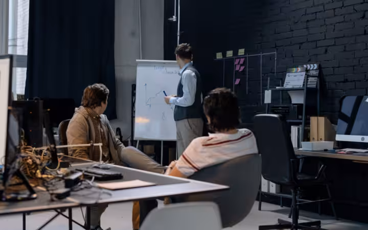 Three people in a modern office with a presentation on growth charts