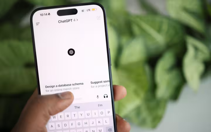 hand holding smartphone showing ChatGPT interface with greenery background