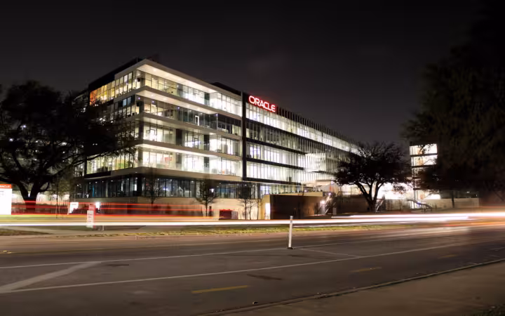 Oracle Riverside Campus illuminated at night across a wide road in Austin