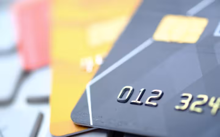 Close-up of overlapping credit and debit cards with embossed numbers.