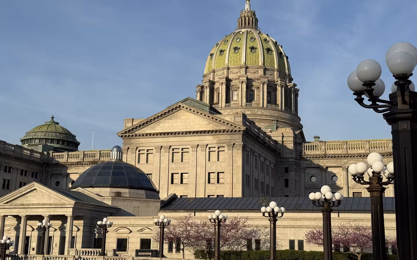 Pennsylvania State Capitol dome rises above its east wing and ornate lamps